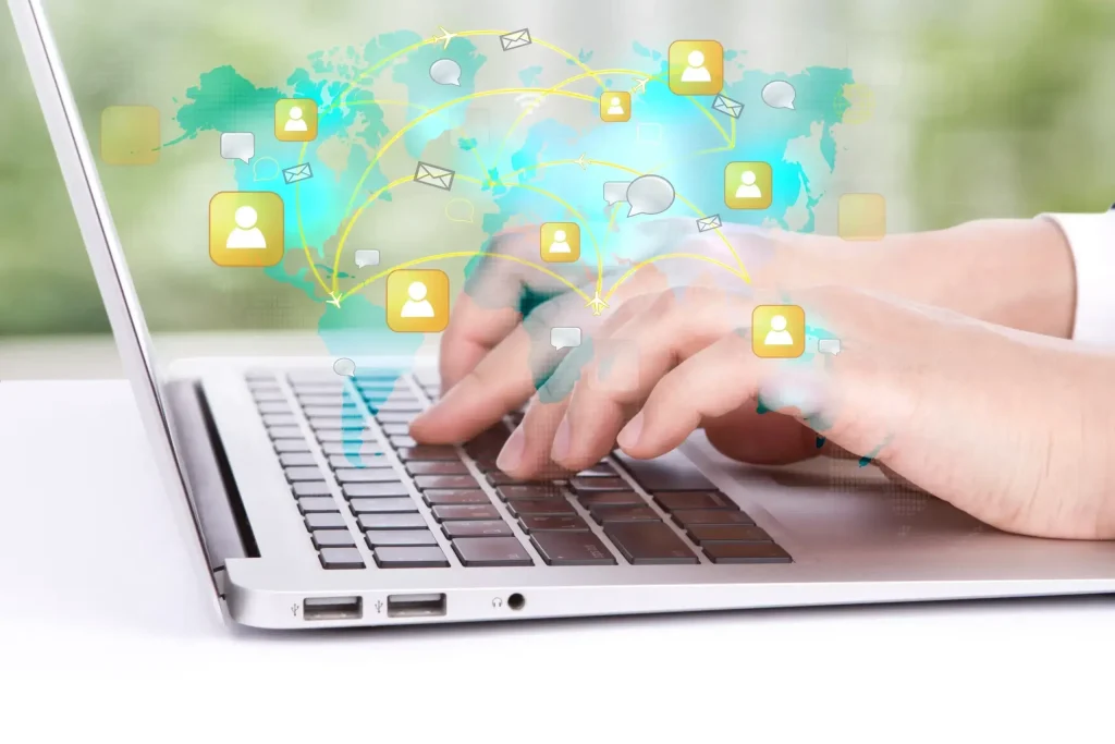 Hands typing on a laptop with global communication icons overlayed, symbolizing internet connectivity and digital interaction.
